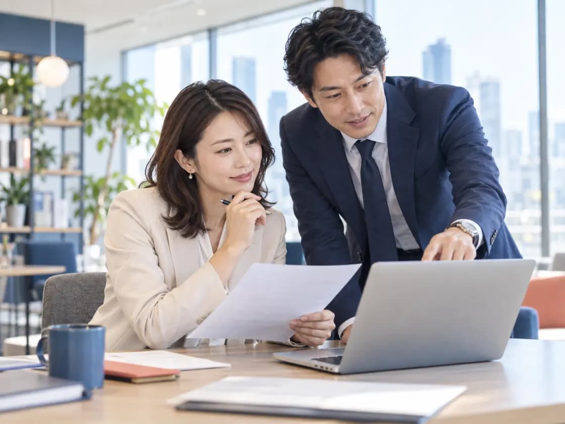 書類とパソコンを見ながら内容を確認するチームのイメージ写真